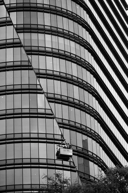 Des professionnels nettoient des vitres de gratte-ciel en milieu urbain en utilisant des cordes.